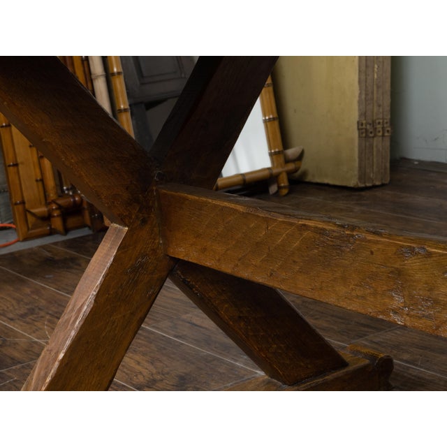 An English oak sawbuck farm table from the 19th century, with double X-Form base, plain cross stretcher and great rustic...