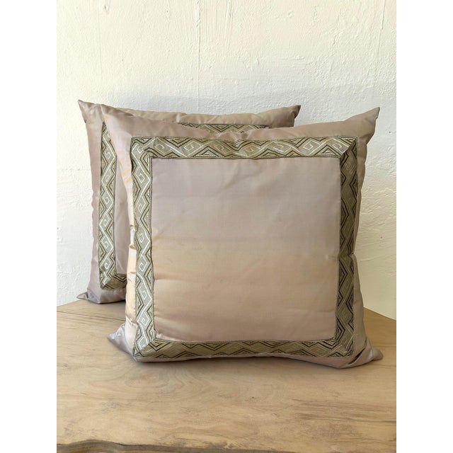 A pair of elegant, silk pillows with inset, modern tape trim on fronts. Custom-made and one-of-a-kind, these pillows will...