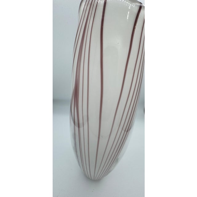Elegant handblown art glass vase featuring flowing amethyst-purple ribbon detailing suspended within a clear glass body....