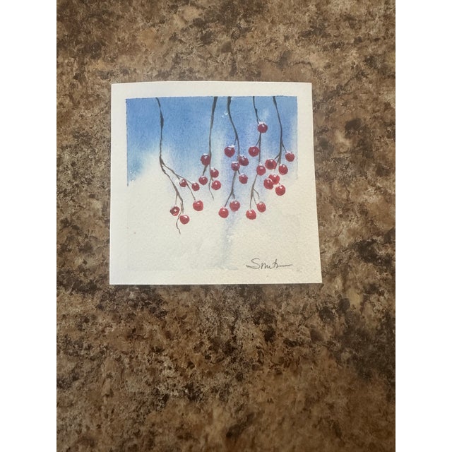 A delicate cluster of crimson winter berries hangs quietly against a soft, frost-blue sky. Minimalist branches and gentle...