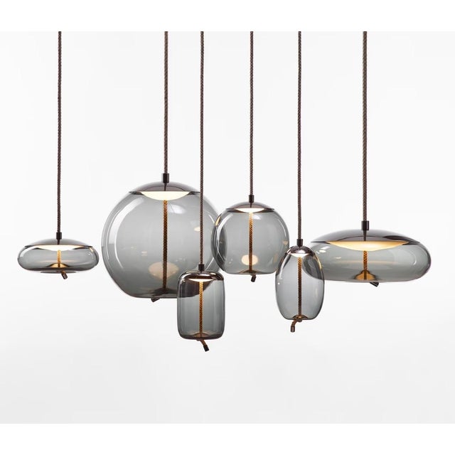 Brokis “Knot” suspension lamp in transparent smoke-grey glass, featuring an elegant brass body finishing and matching...