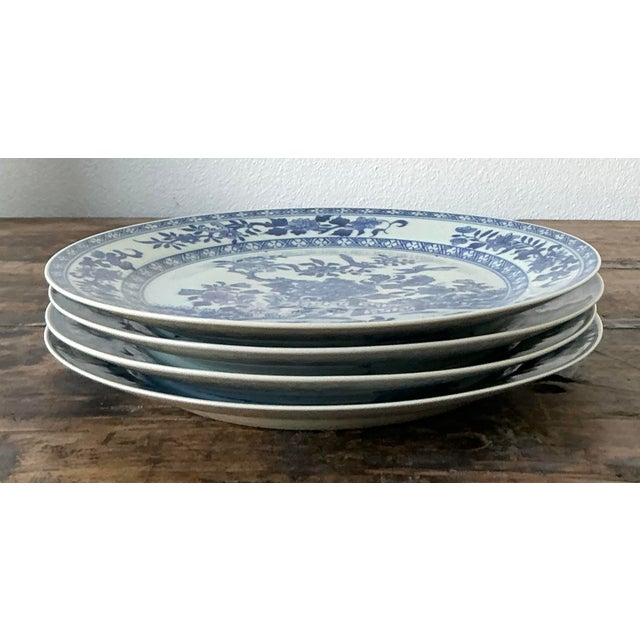 This elegant set of four vintage blue and white ceramic plates captures the timeless allure of classic Chinoiserie design....