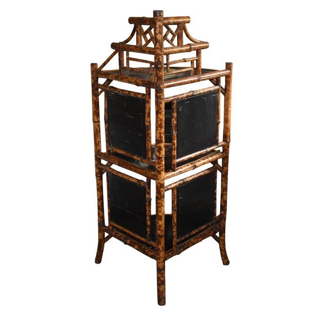 An antique English 3 tier corner etagere of burnt bamboo and black Japanned panels. Each shelf is fan-shaped and Japanned...