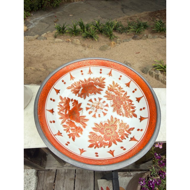 A beautifully detailed Japanese porcelain ware bowl featuring intricate floral motifs in warm rust-red and gold tones,...