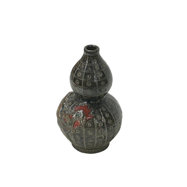 This striking double-gourd ceramic vase features a rich, dark metallic glaze with a distinctive "coin" or "eye" geometric...