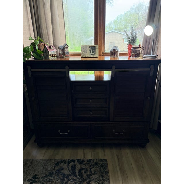 This impressive transitional sideboard offers a sophisticated blend of traditional mahogany veneers and rustic industrial...