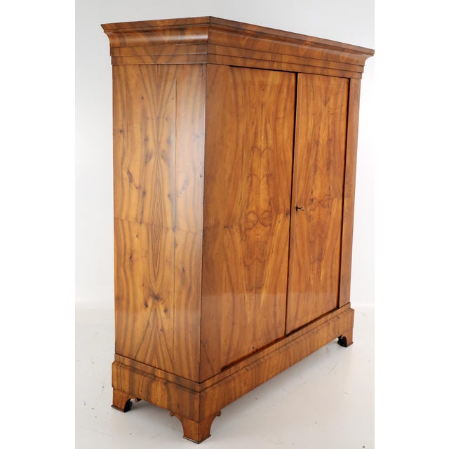 Original Biedermeier wardrobe in walnut veneer with a large cornice, beautiful framed panels on the front, two doors in...