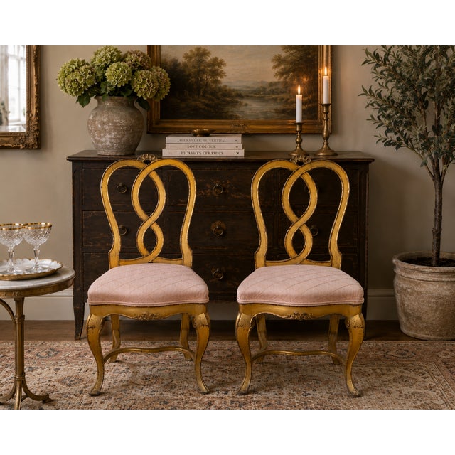 A striking pair of gilded Hollywood Regency side chairs in the style of Rose Tarlow, featuring sculptural ribbon-form...