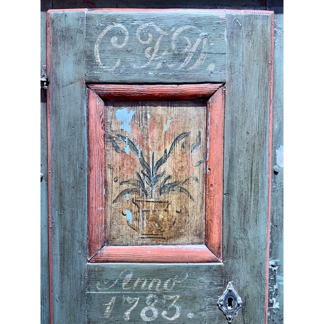 A late 18th-century Scandinavian folk art corner cabinet with a blue-green painted finish, red trim, and hand-painted...