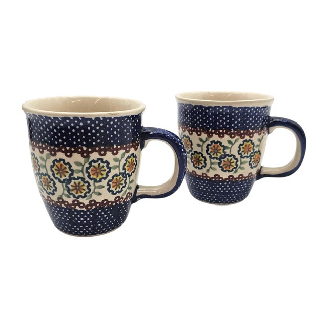 A duet of delight, these hand-painted Polish stoneware mugs sing in cobalt and cream. Delicate florals bloom in golden...