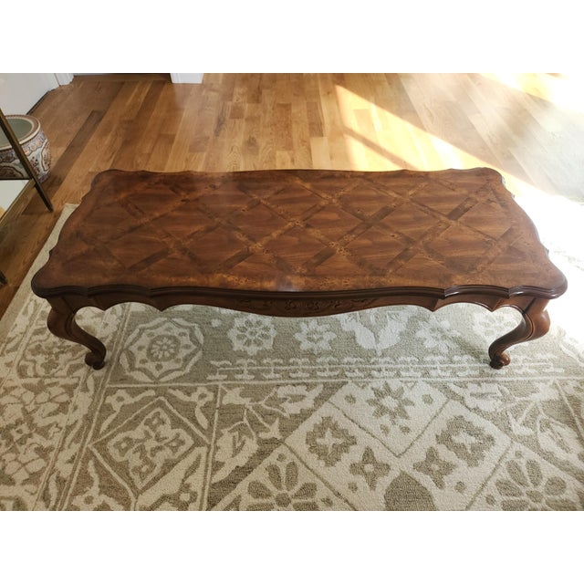 A vintage French Provincial style coffe table with a scalloped-edge, stunning parquetry tabletop and cabriole legs. The...