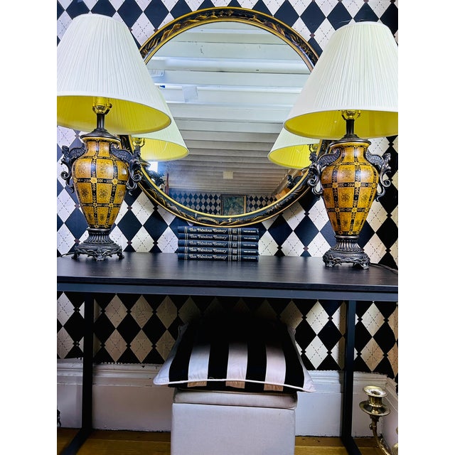 An oversized round wall mirror featuring a black lacquer frame with hand-painted gold scenic decoration inspired by...