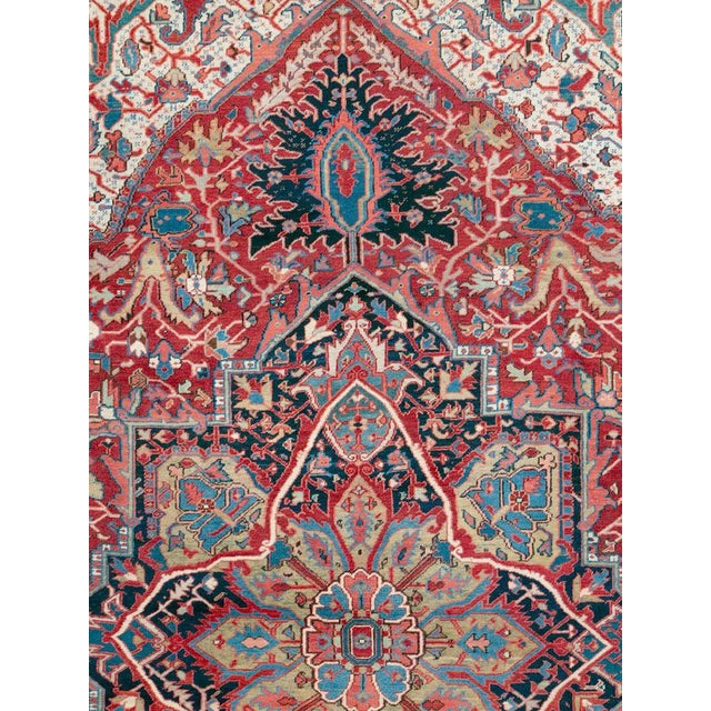 This early 20th-century Persian Heriz room-size carpet presents a bold central medallion composition in rich brick red,...