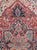 This early 20th-century Persian Heriz room-size carpet presents a bold central medallion composition in rich brick red,...