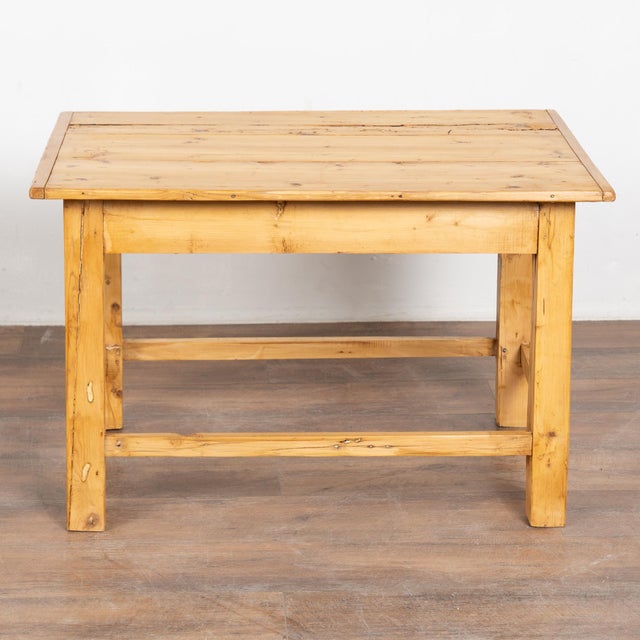 Rustic 20th century short side table, crafted in pine. The table stands on four square legs joined by a simple trestle...