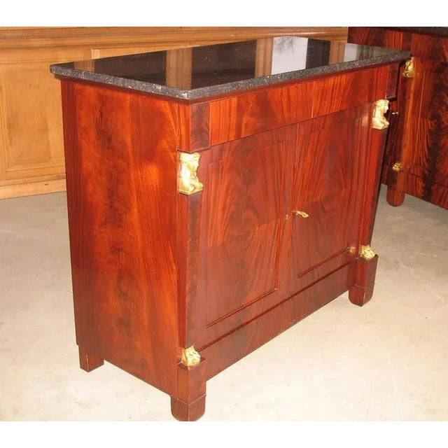 Small "Return of Egypt" style buffet in flamed mahogany veneer opening at 2 doors and 2 drawers. Black marble top. Bronze...