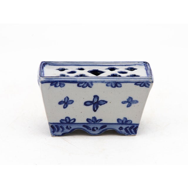 A petite Dutch Delft-style blue and white porcelain flower frog or brick with a scalloped foot and trapezoid profile. The...