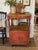 Charming primitive tea cabinet featuring original hand-painted folk art details, a beautifully weathered wood top, turned...