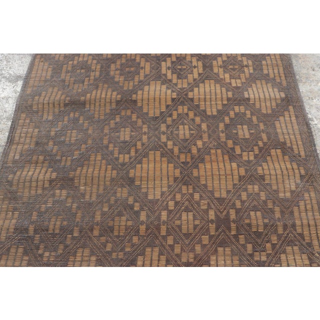 Made with handwoven reed and camel leather in Mauritania circa 1950-1960, this 3x5 vintage Tuareg mat is an exceptional...