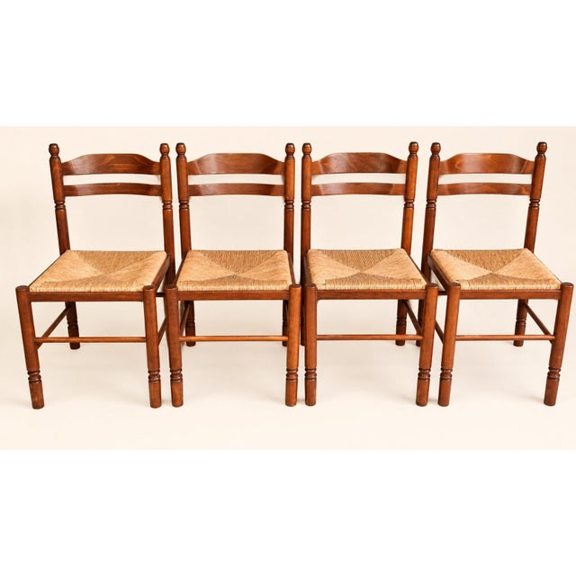 A set of four french provincial-style dining chairs, crafted from fruitwood stained a mahogany brown, dating from the...