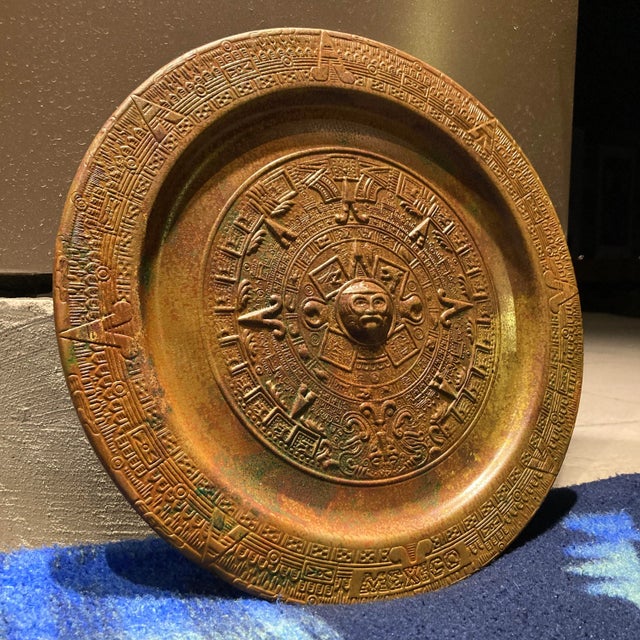 Solid brass Mayan sun god calendar hand chiseled decorative wall plate, circa mid-twentieth century Mexico.