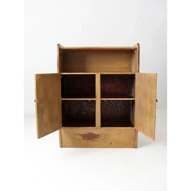 A late 19th century antique cabinet in primitive style, featuring double doors that conceal two shelves, topped by an open...