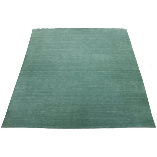 This handcrafted custom wool rug, designed in the Gabbeh style, features a solid green design. It is part of our Desert...