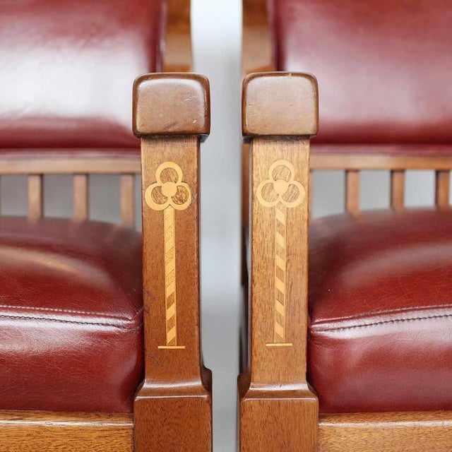 A pair of arts & crafts armchairs. Solid walnut frames, with satinwood inlay. Upholstered in chestnut leather. Dimensions:...