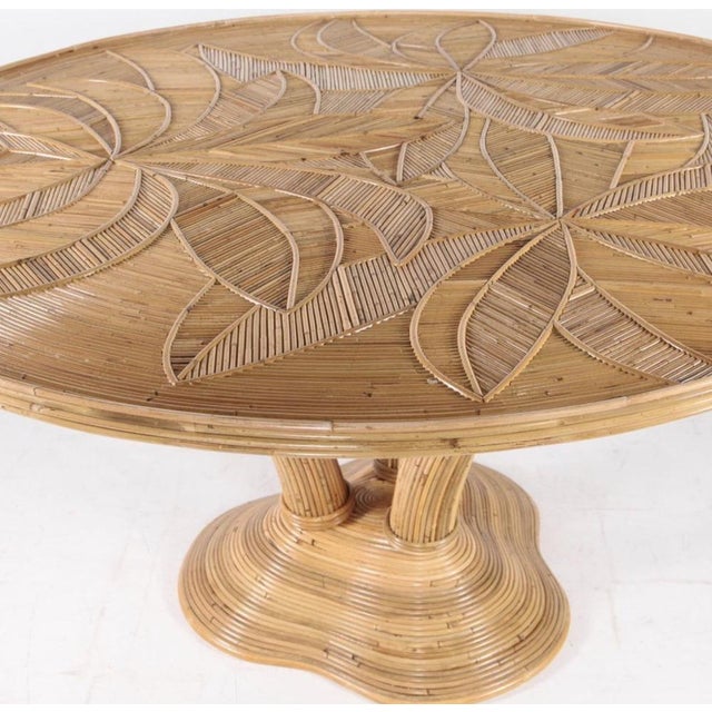 Exceptional round rattan dining table. Legs representing a palmtree, top with palms patterns covered with a glass top....