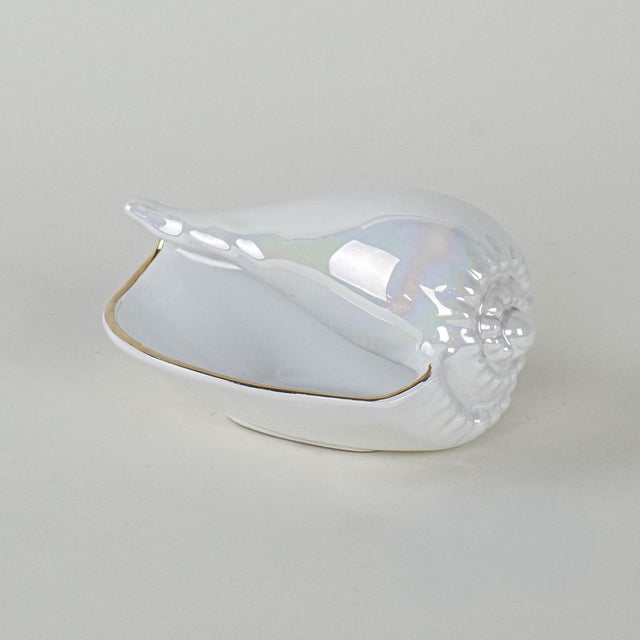 The shell was made in the 1970s in Italy. A white porcelain shell with a shiny, iridescent coating and subtle gold edging....