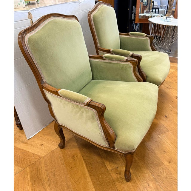Pair of elegant French bergère armchairs featuring gracefully carved wood frames and classic cabriole legs. Upholstered in...