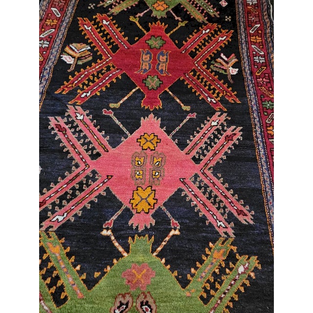 A captivating vintage Karabagh rug featuring an elegant deep black background embellished with four large polychrome...