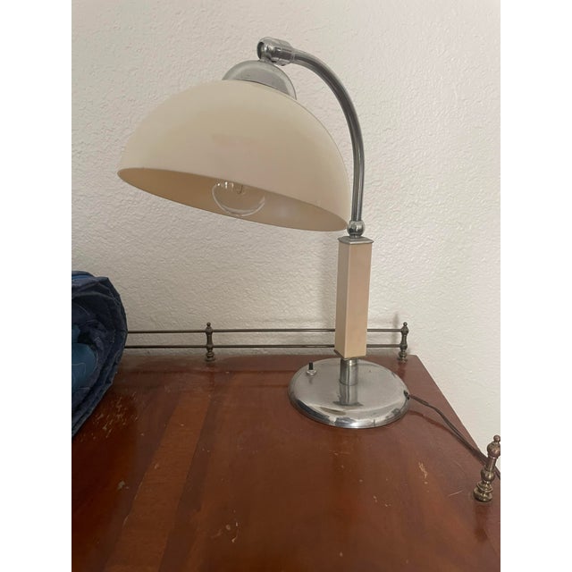 A striking vintage Bauhaus-style desk lamp featuring clean geometric lines, a sculptural chrome frame, and a cream metal...