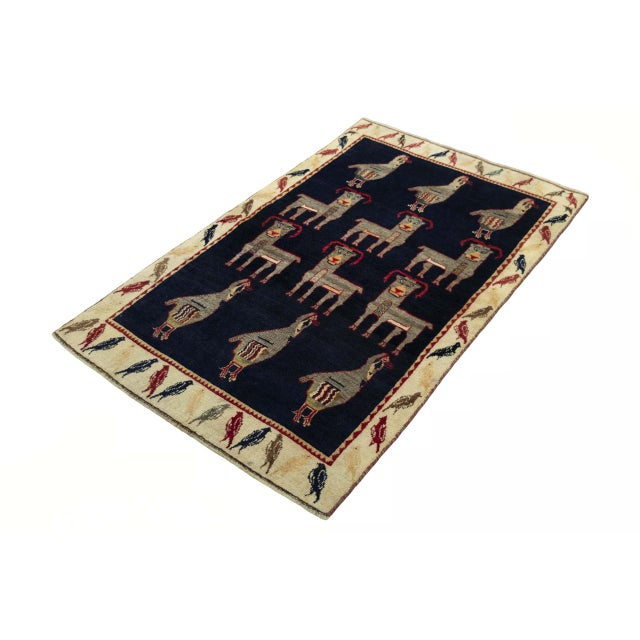 An extraordinary hand-knotted Gabbeh nomadic rug with characteristic animal motifs. The deep blue base color impressively...