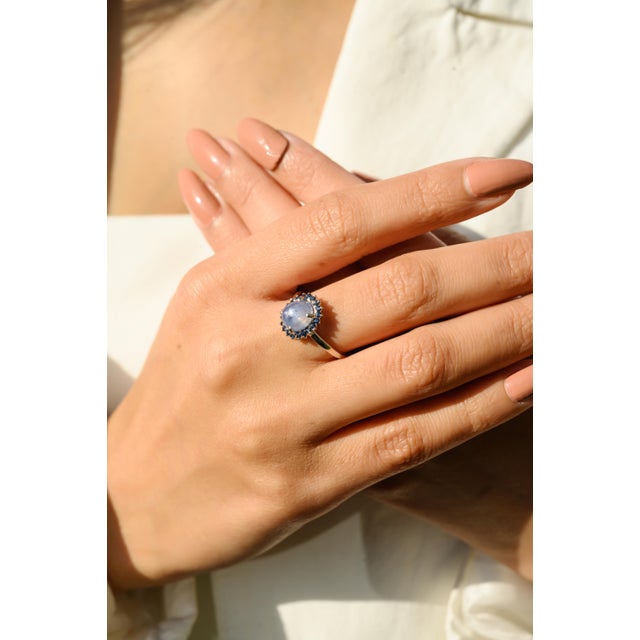 This elegant ring features a 1 oval cut captivating natural cabochon blue star sapphire at the center, weighing...