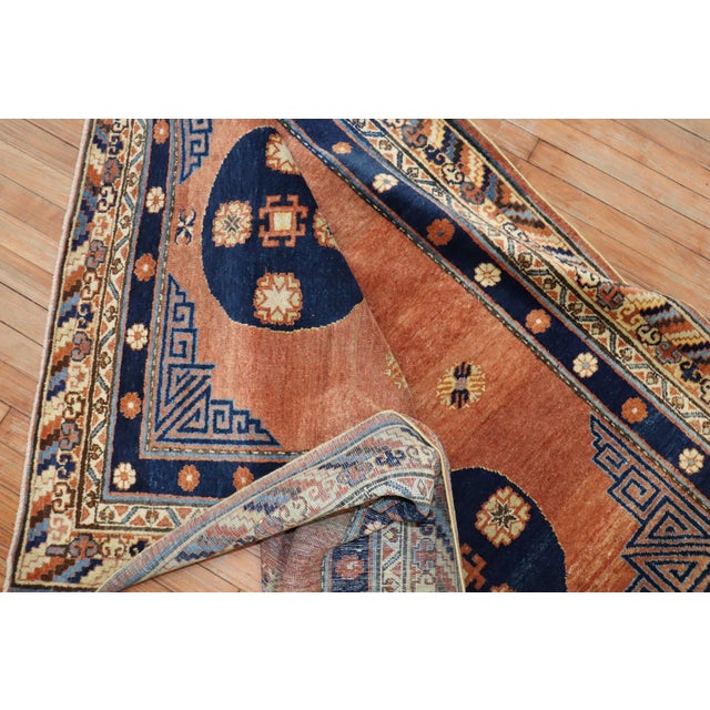 An early 20th century Khotan rug in salmon and navy blue hues part of a pair