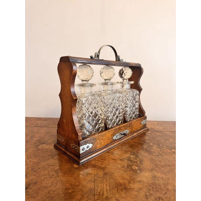 Quality antique Victorian oak tantalus, having three quality cut glass decanters with the original stoppers, in an oak...