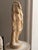 A weathered alabaster torso in the Grand Tour tradition, carved as a draped classical female figure with one arm raised to...