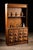 This 1920s apothecary hutch features porcelain drawer pulls labeled with different medicines and medical tools to aid in...