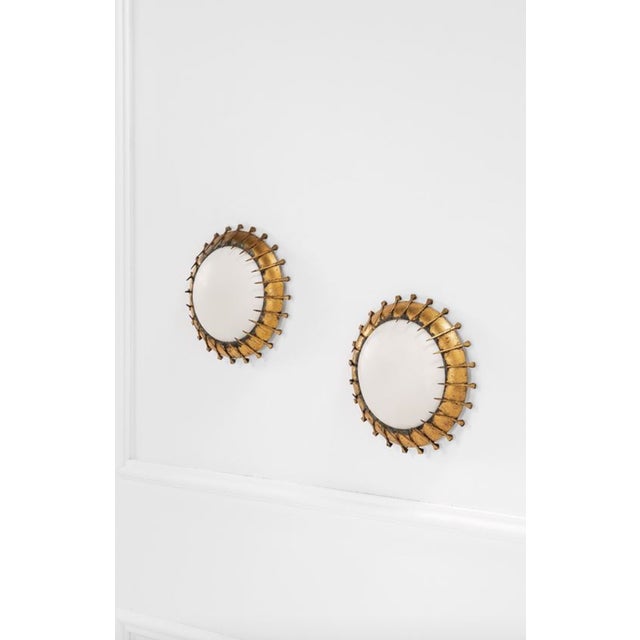 A Set of 2 Brutalist sconces. France 1960s. Gilded and corroded metal, curved opaline satin glass. Diam. 25 cm, depth 8...