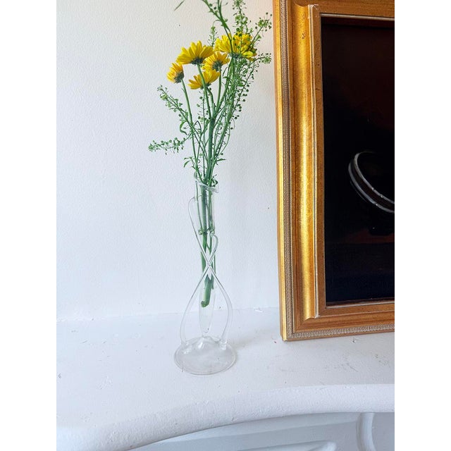 Clear borosilicate glass forms a twisted, serpentine vase with a flared, uneven rim that gently undulates like a tulip or...