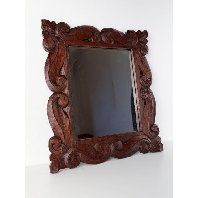 Beautiful vintage wall mirror with an ornate hand-carved wooden frame featuring flowing scroll and foliate motifs. The...