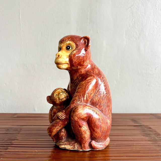 This ceramic sculpture captures a tender moment between a mother monkey and her baby, rendered with expressive detail and...