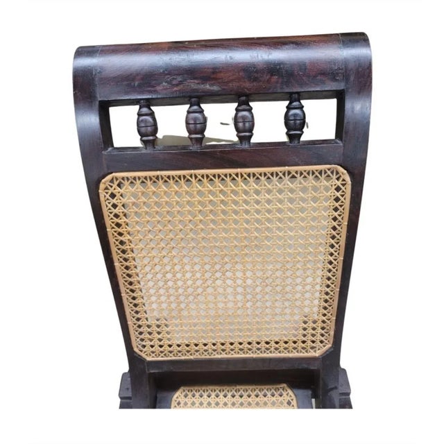 A pair of folding Anglo Indian slipper lounge chairs that evokes the romance of a 1920s ship's voyage across the Indian...