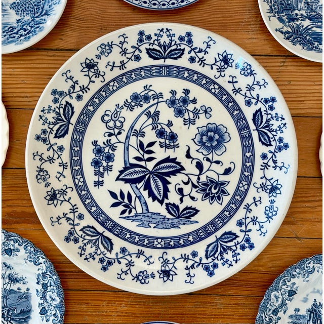 A classic blue and white wall plate layout with carefully collected vintage and antique plates. The center plate is...