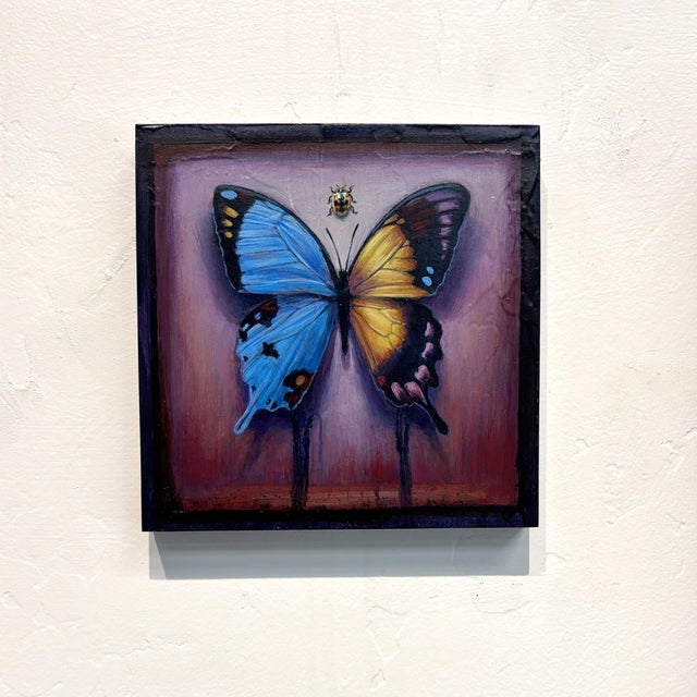 This artwork features a striking hybrid butterfly, its wings painted in vibrant shades of blue and orange, creating a...