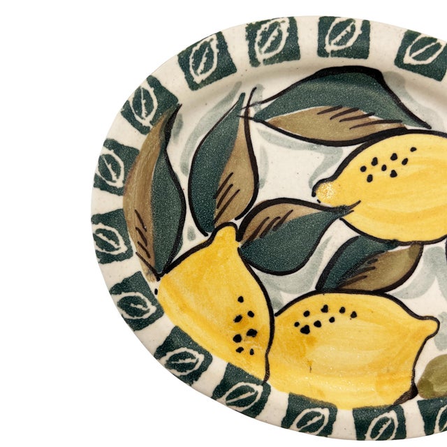 A beautifully hand-painted Italian ceramic lemon dish, featuring a vibrant trio of sun-ripened lemons nestled among deep...