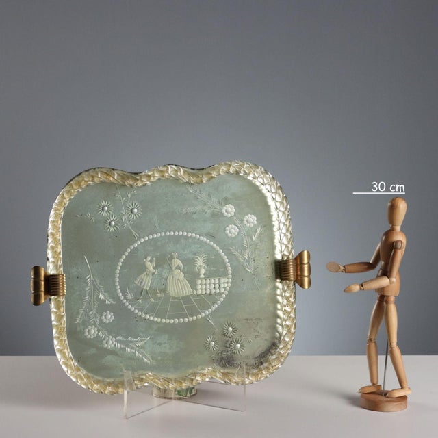 An engraved mirror tray with a central decoration depicting a romantic scene enclosed in a reserve and surrounding...
