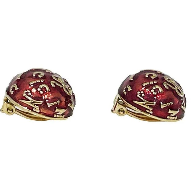 French red and gold tone ear clips by Nina Ricci, 1980s Ear clips with domed base with raised letters in gold tone from...