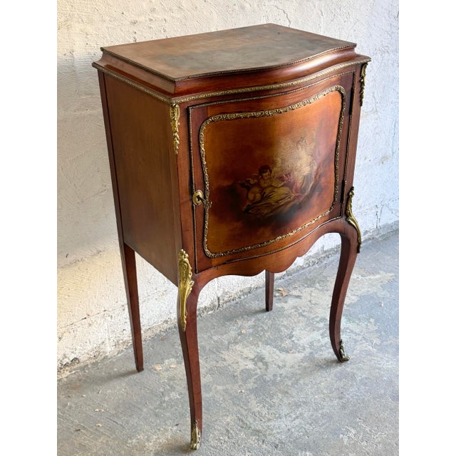 An antique French Vernis Martin decorated music cabinet offers kingwood construction in bombe form with cast ormolu...